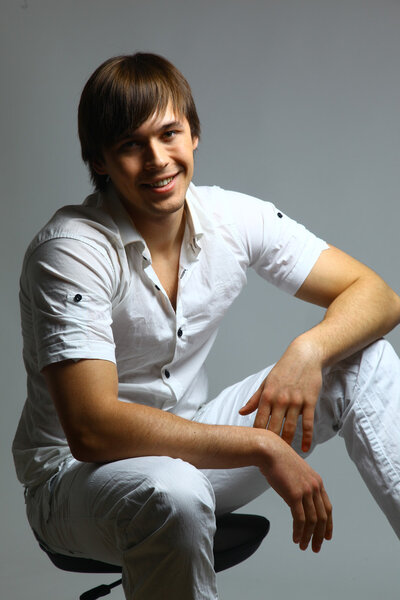 Portrait of a casual young satisfied man sitting relaxed. Isolated on white