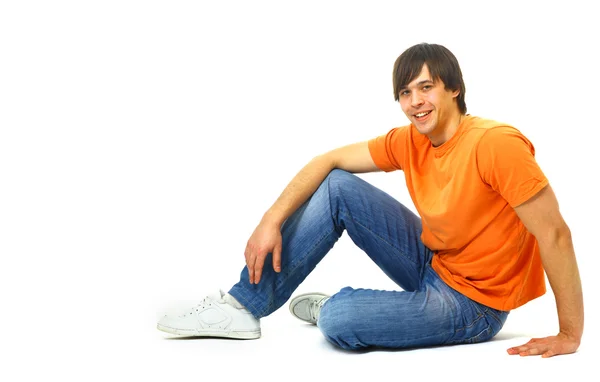 Portrait of a casual young satisfied man sitting relaxed. Isolated on whi — Stock Photo, Image