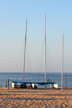 Catamarans lined up on a beach clipart