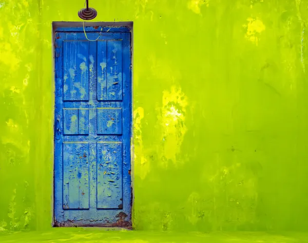 ぼろぼろの緑の壁の青いドア — ストック写真