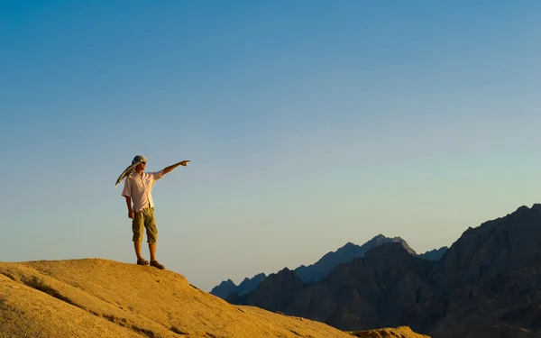Mann steht auf Felsgipfel in Wüste Stockbild