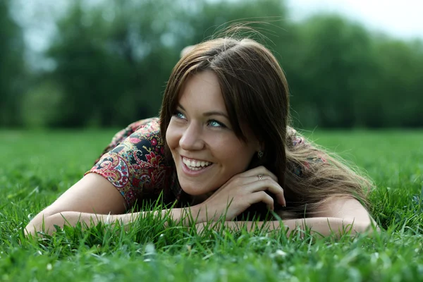 Vacker ung kvinna kopplar av i gräset — Stockfoto