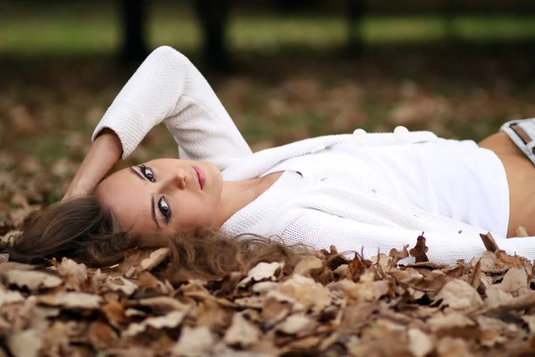 Schönes Mädchen liegt auf der Erde, Eichenblätter — Stockfoto