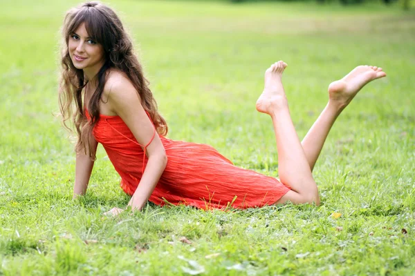 Güzel bir genç kadın çimenlerde rahatlatıcı — Stok fotoğraf
