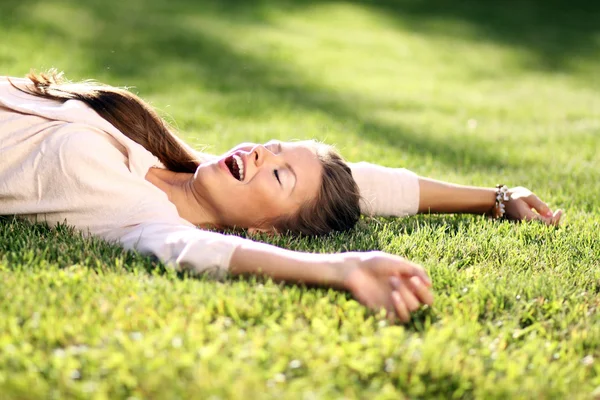 Žena leží na travnaté hřiště v parku — Stock fotografie