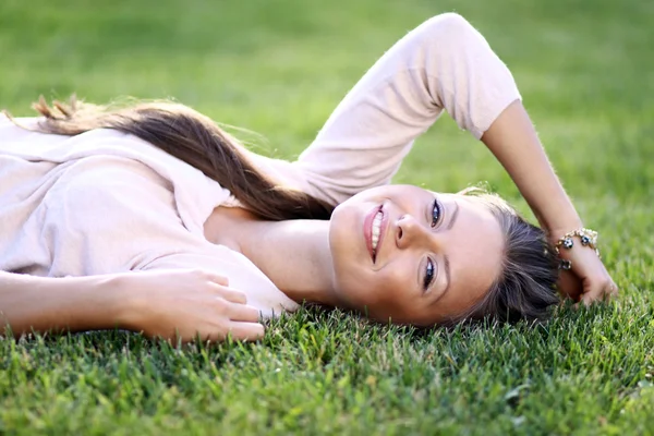 Aranyos fiatal nő, fekvő, füves területen, a parkban — Stock Fotó