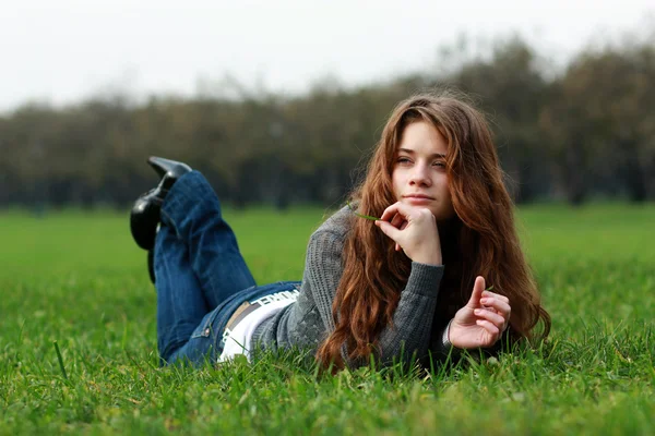 Vacker ung kvinna kopplar av i gräset — Stockfoto