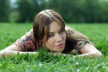 Genç kadın çimenlerde dinleniyor.