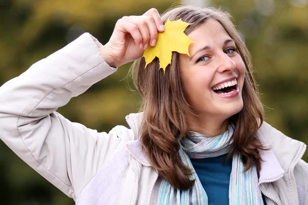 Brünette mit goldenem Herbstblatt — Stockfoto