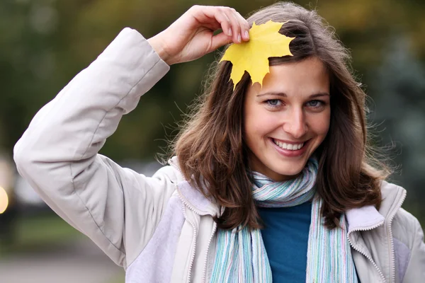 Brunette with golden autumn leaf — Stock Photo, Image