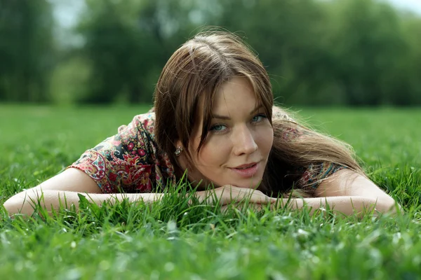 Genç kadın çimenlerde dinleniyor. — Stok fotoğraf