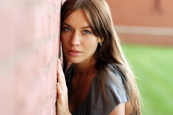 Beautiful woman standing against wall — Stock Photo, Image