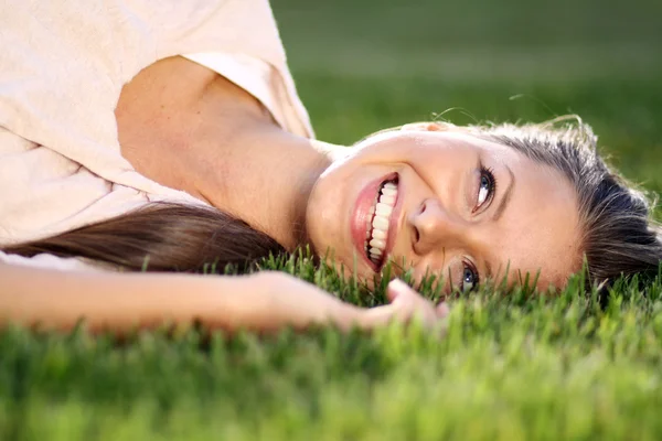 Cute young female lying on grass field — Stock Photo, Image