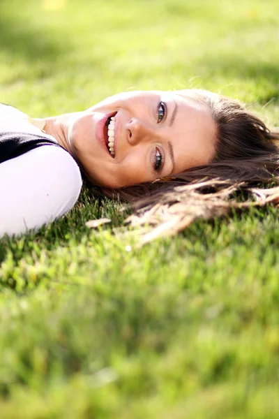 Schattige jonge vrouwelijke liggend op grasveld in het park — Stockfoto
