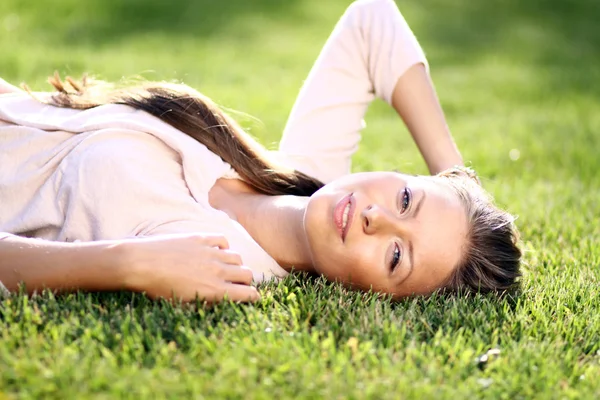 Schattige jonge vrouwelijke liggend op grasveld in het park — Stockfoto