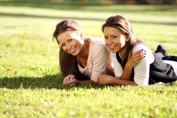 Beautiful twins of sister lays on green — Stock Photo, Image