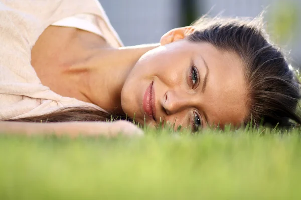 Roztomilá mladá žena leží na travnaté hřiště Royalty Free Stock Fotografie