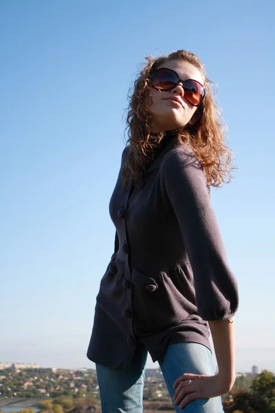 Dívka představuje proti modré obloze — Stock fotografie