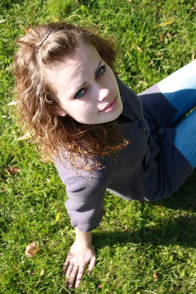 Meisje zit op een groen gras — Stockfoto