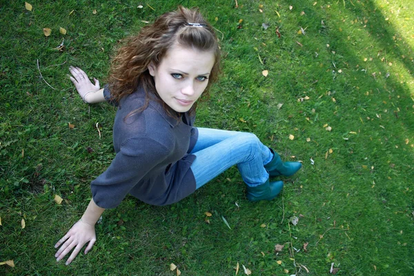 Girl sits on a green grass — Stock Photo, Image
