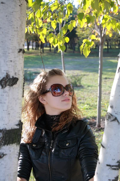 Chica joven cuesta cerca de un árbol —  Fotos de Stock
