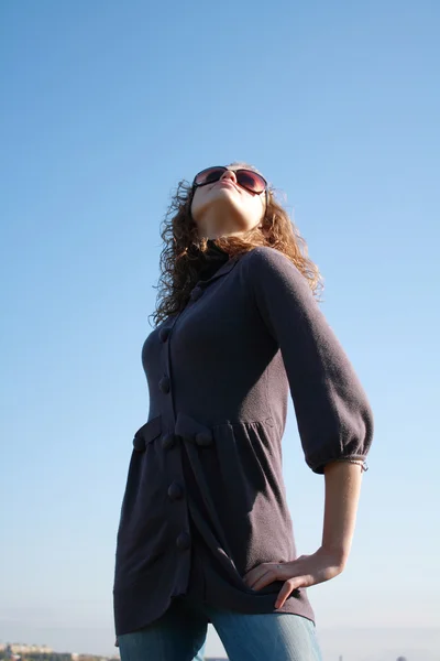 Mulher posa contra o céu azul — Fotografia de Stock