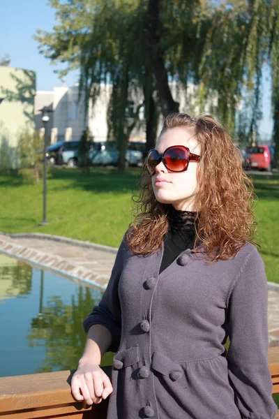 Девушка стоит на мосту в солнечных очках — стоковое фото