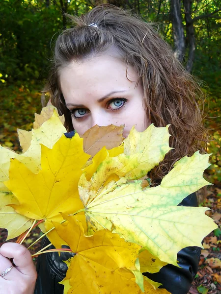 Chica sostiene hojas amarillas en una mano —  Fotos de Stock