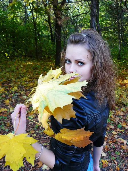 Chica sostiene hojas amarillas en una mano —  Fotos de Stock