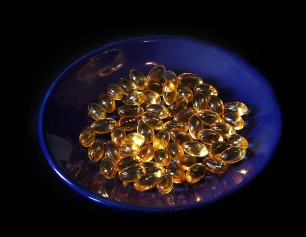 Yellow pills on a blue saucer — Stock Photo, Image