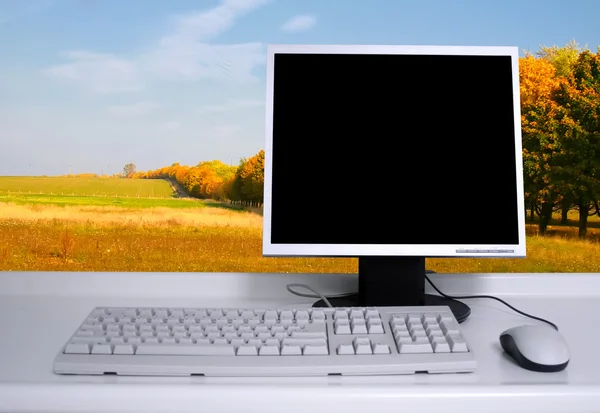 PC med svart skrivbord och höstträd — Stockfoto