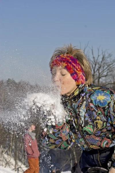 Η νεαρή γυναίκα φυσήξει το χιόνι — Φωτογραφία Αρχείου