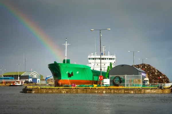 Cargo ship in docks and rainbow — Stock Photo, Image