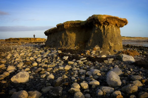 Lone cliff on stony beach and man — Stock Photo, Image