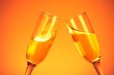 Pair of champagne flutes on orange backg clipart