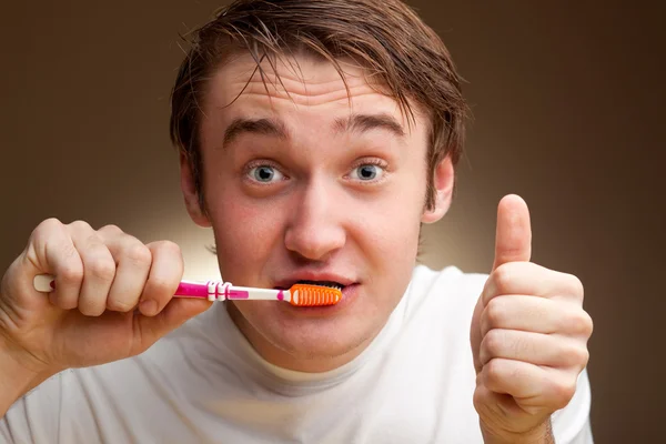 Ein lustiger junger Mann putzt Zähne. — Stockfoto