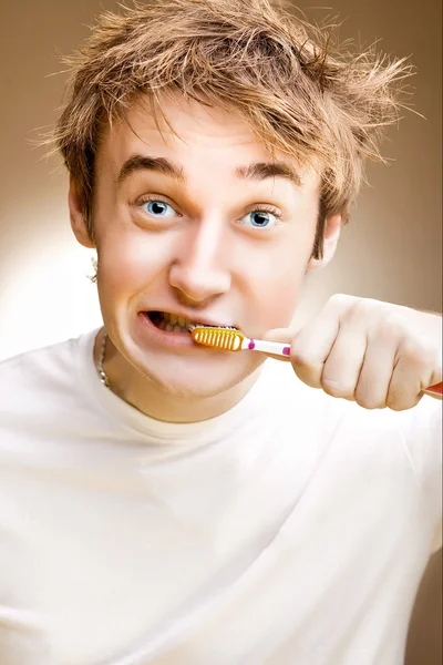 Ένα αστείο νεαρός καθαρίζει τα δόντια. ήπια. — Φωτογραφία Αρχείου