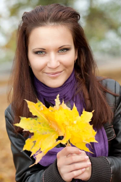 Chica feliz con hojas amarillas y sonrisas — Foto de Stock