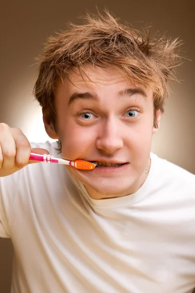 Ein lustiger junger Mann putzt Zähne. gemildert. — Stockfoto