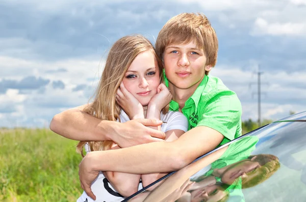 Meisje en jongen op de auto in het veld — Stockfoto