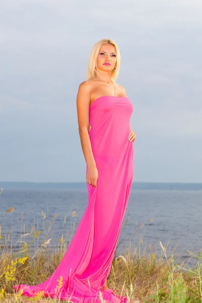 Hermosa chica en un vestido largo rosa . — Foto de Stock