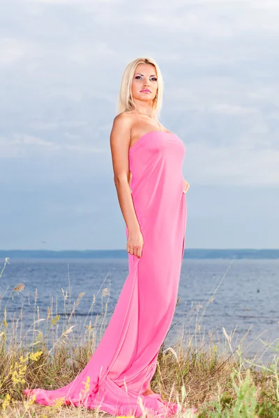 Vacker flicka i en lång rosa klänning. — Stockfoto