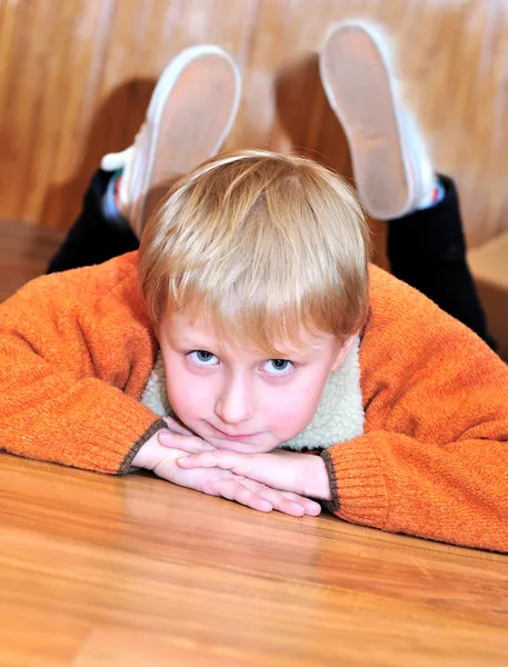 Маленький мальчик лежит на деревянном полу — стоковое фото
