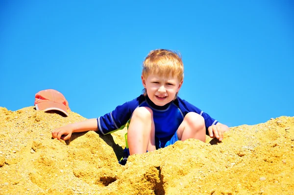 Хлопчик сидить у величезному купа піску — стокове фото