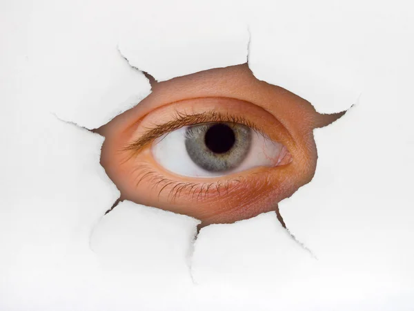 Occhio che guarda attraverso il buco sulla carta — Foto Stock