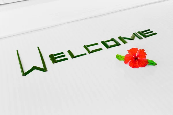 Palabra Bienvenida y flor en la cama en el hotel — Foto de Stock