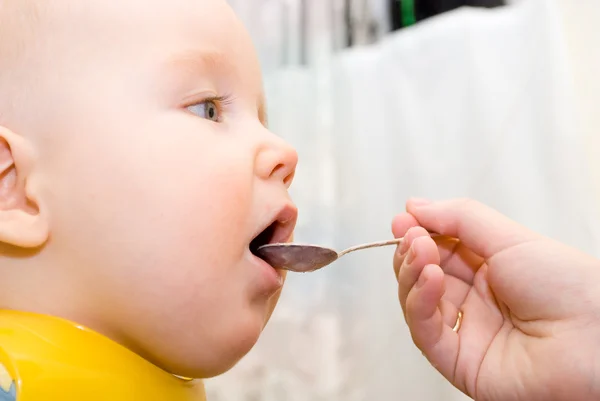 A criança come de uma colher — Fotografia de Stock