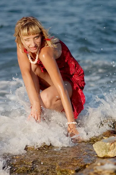 Femme en robe rouge en étincelles de mer — Photo