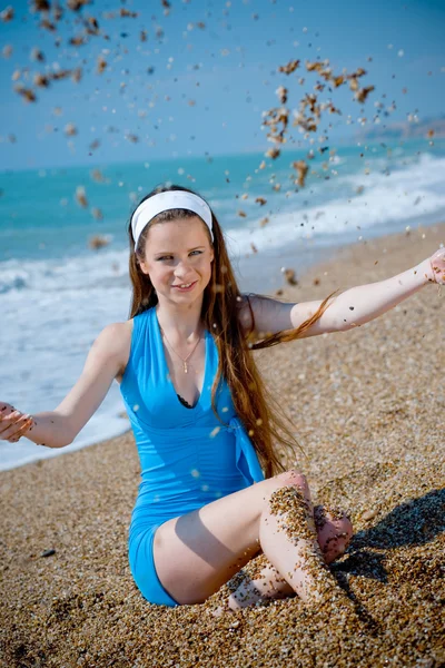 Женщина играет с песком на пляже — стоковое фото