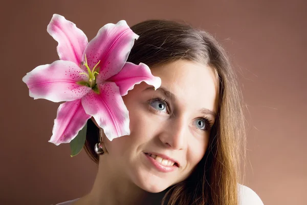 Ung kvinna poserar med en rosa Lilja — Stockfoto